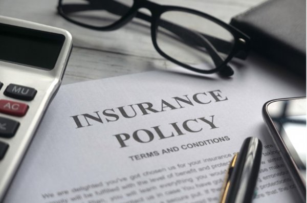 A pair of glasses and a pen laying on piece of paper text reads Insurance policy