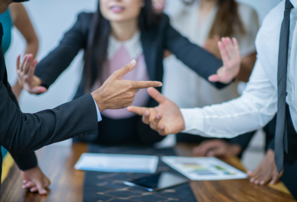 two people pointing at each other and a mediator in the background with her hands up