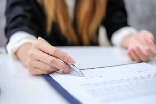 closeup of a business woman signing documents with a pen