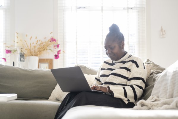 woman sitting on sofa looking at laptop