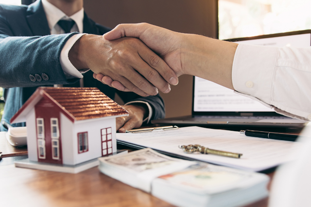 Two people shaking hands over money and a contract