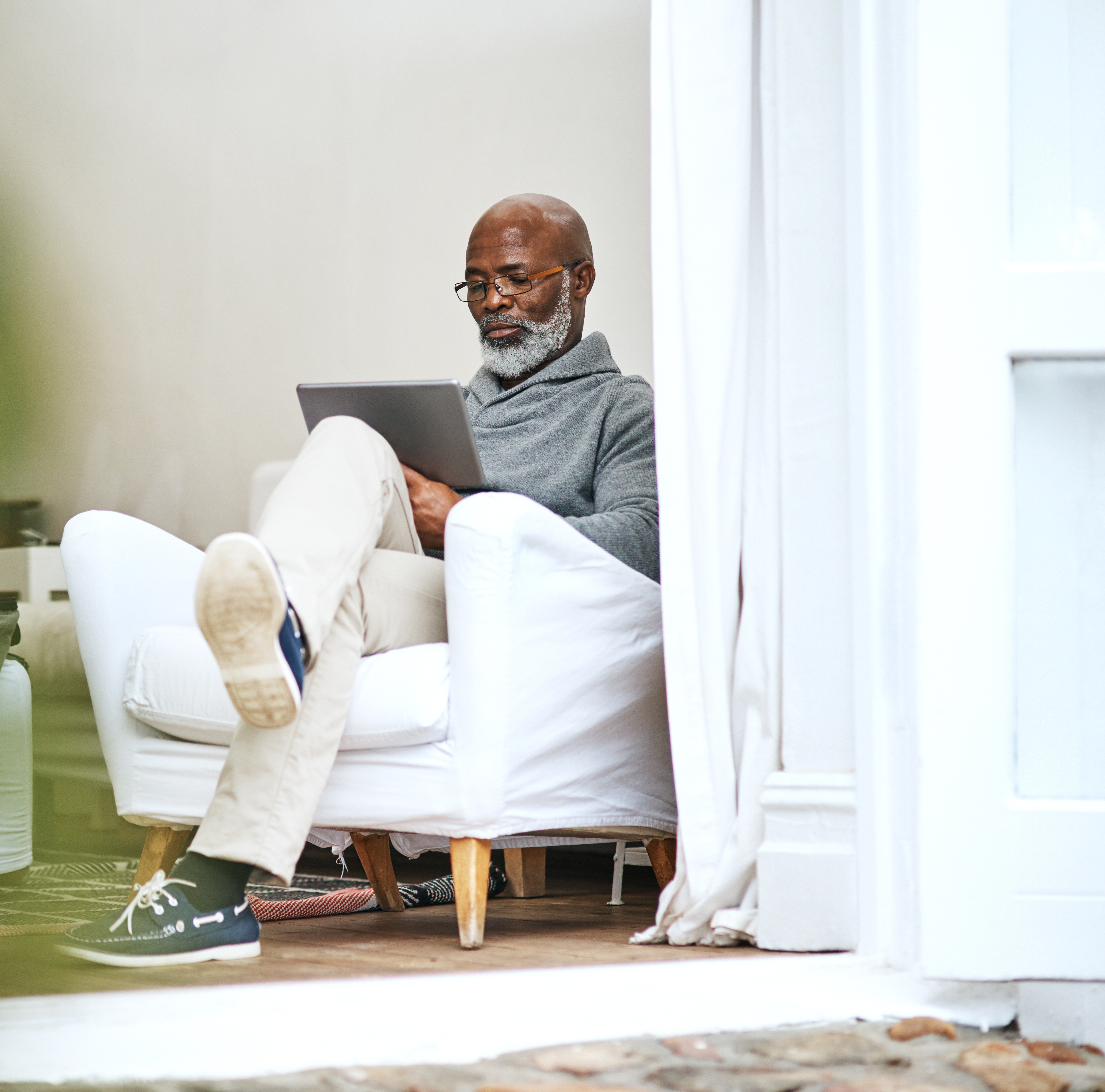 man sitting in a chair, looking at a tablet