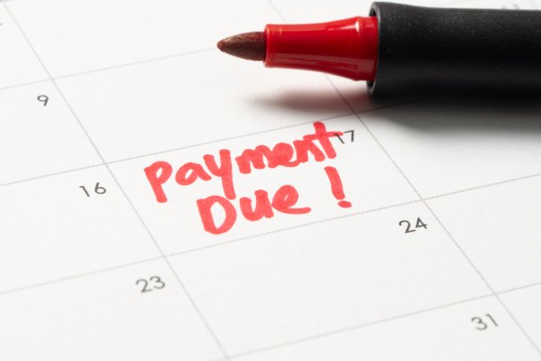closeup of a paper calendar with the words, "payment due!" written in red marker in the 17th box.