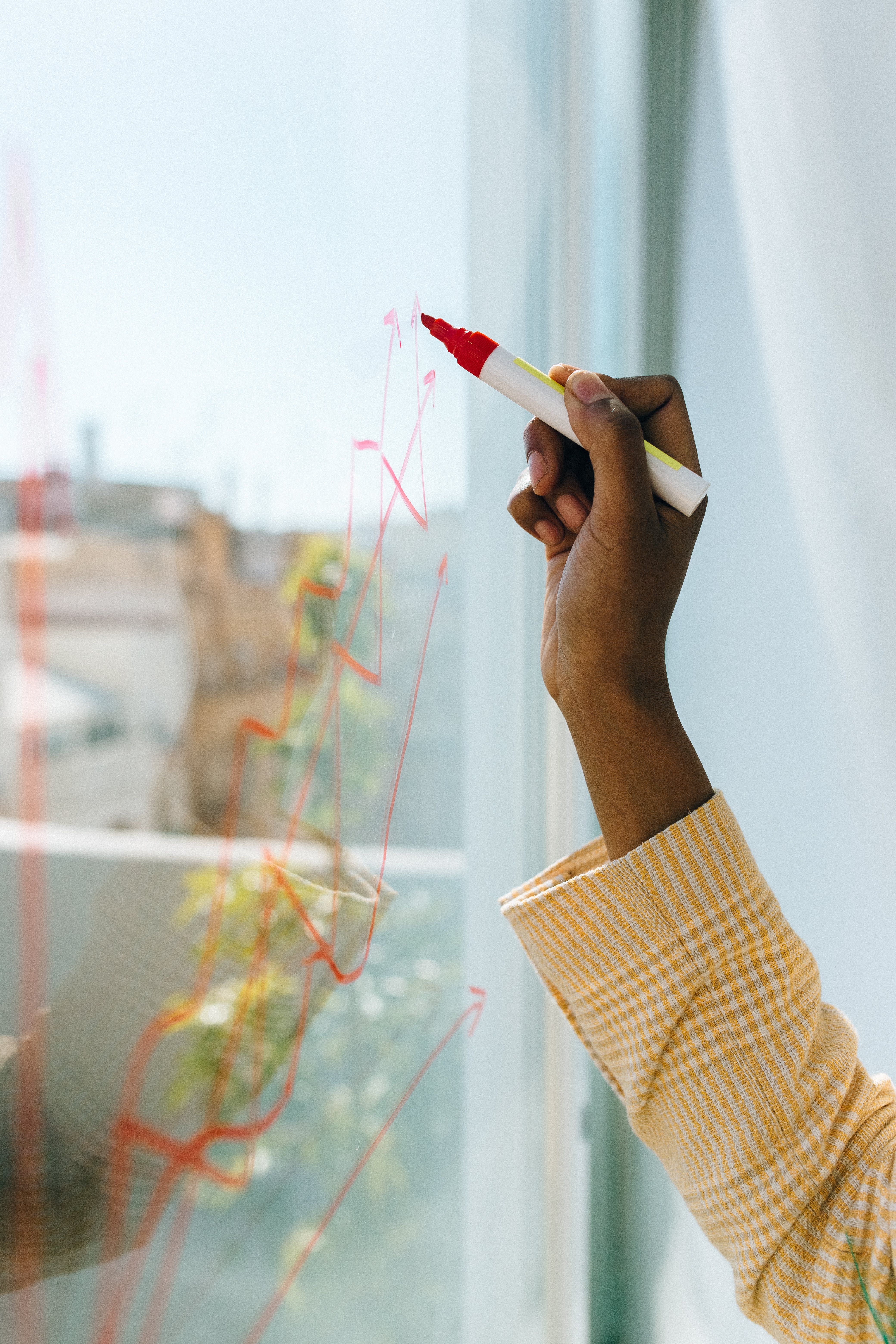 A person writing on a piece of glass with a marker.