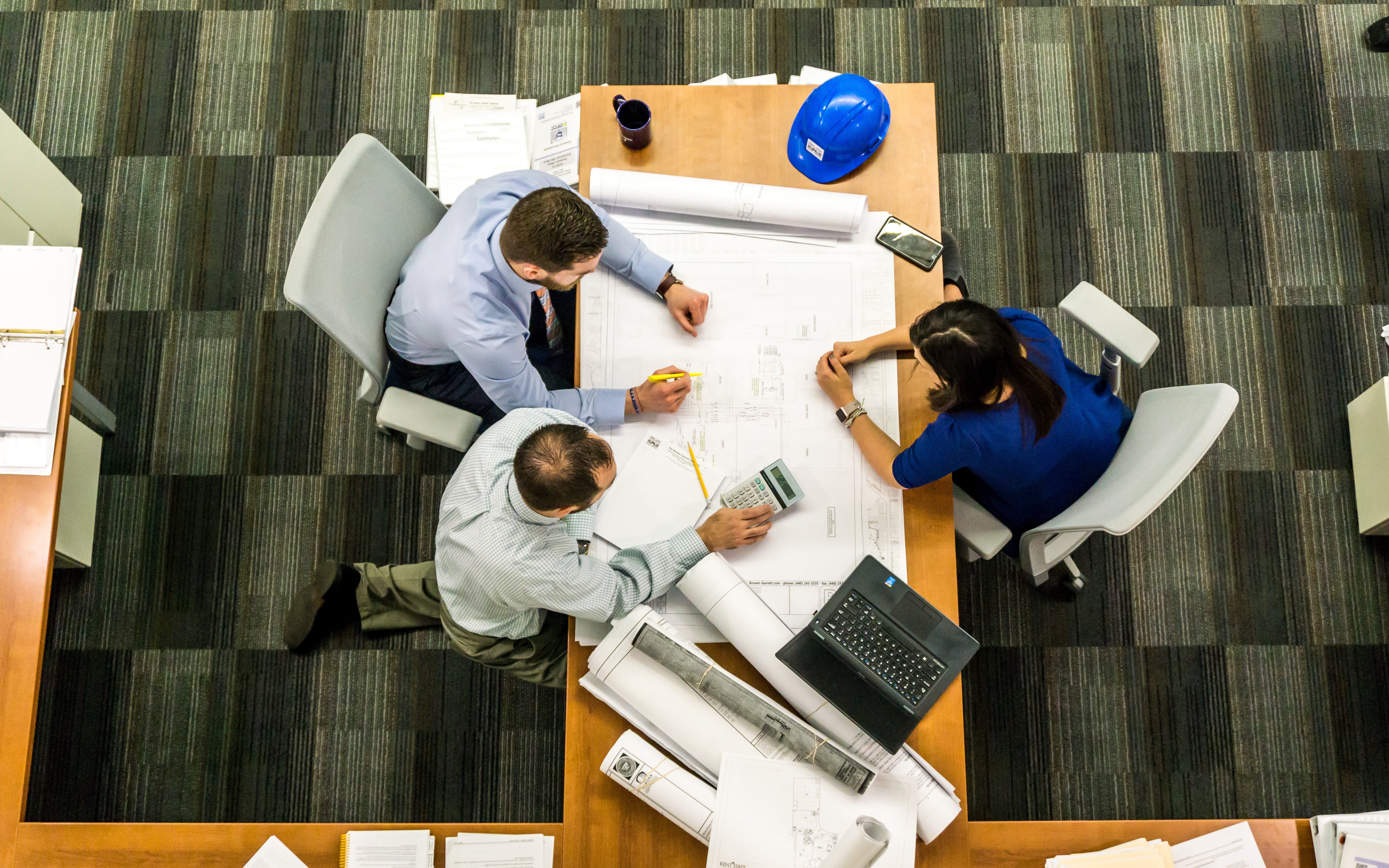 Top view of 3 people sitting at a table working