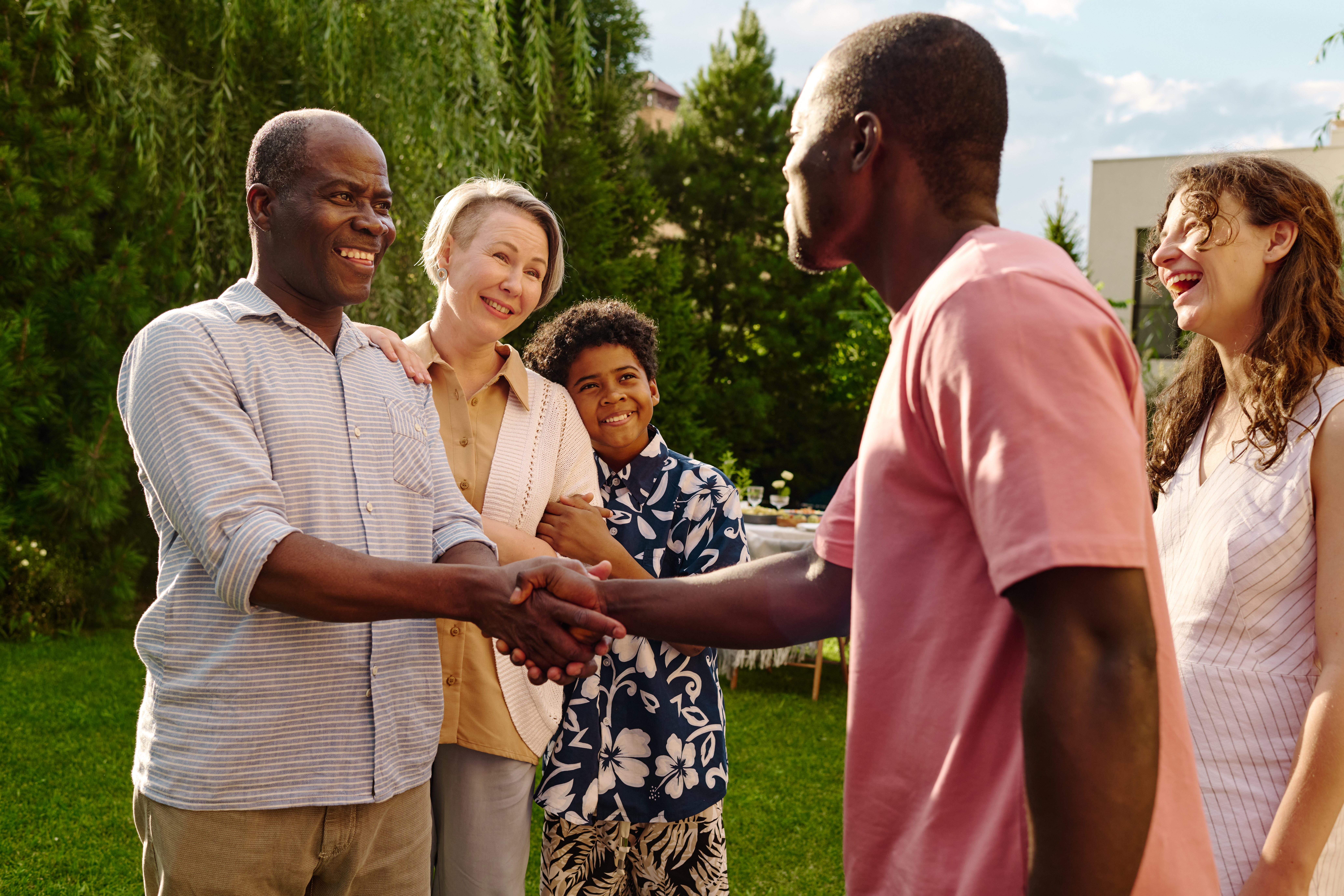 two happy men shaking hands as family stands closeby