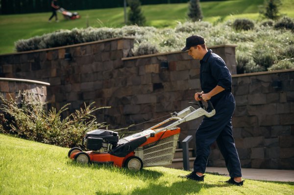 man cutting grass with a push lawn mower