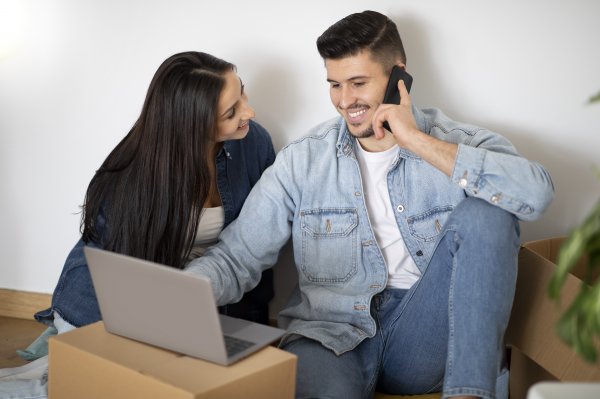 young couple with laptop and phone, smiling
